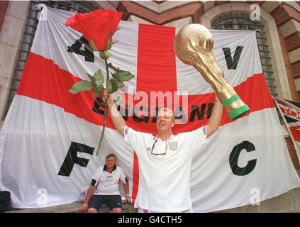 Ashley White, fan patriotique de football anglais, se dresse devant un immense drapeau de St George hissé sur le mur de l'hôtel de ville de Toulouse aujourd'hui (lundi) alors qu'il détient une rose anglaise géante et un modèle du trophée de la coupe du monde. Des milliers de fans se sont réunis dans le centre de la ville française où l'Angleterre affronte leur deuxième affrontement de tournoi contre la Roumanie plus tard dans la soirée. Photo de Peter Jordan/PA Banque D'Images