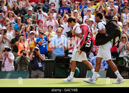 JO Wilfried Tsonga, en France, part du terrain avec Roger Federer, en Suisse, après l'avoir battu en 5 lors du neuvième jour des Championnats de Wimbledon 2011 au All England Lawn tennis and Croquet Club, Wimbledon. Banque D'Images