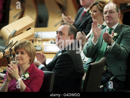 (De gauche à droite) la vice-première ministre et chef adjoint du SNP, Nicola Sturgeon, le premier ministre Alex Salmond et le secrétaire aux Finances, John Swinney, réagissent à une allocution de la reine Elizabeth II lorsqu'elle a officiellement ouvert la quatrième session du Parlement écossais, déclarant que celle-ci a « vraiment pris de l'âge »,Accompagnée de son mari, le duc d'Édimbourg, elle s'est adressée aux MSP et à d'autres invités à l'intérieur de la chambre Holyrood. Banque D'Images