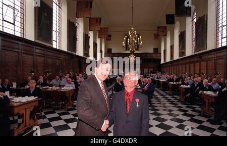 Le secrétaire à la Défense, George Robertson, félicite Joe Scally après avoir reçu son OBE aujourd'hui (mercredi), dans la salle à manger du Royal Hospital Chelsea, où M. Scally a travaillé pendant plus de vingt ans, à l'entretien des bâtiments.Photo de John Stillwell/PA Banque D'Images