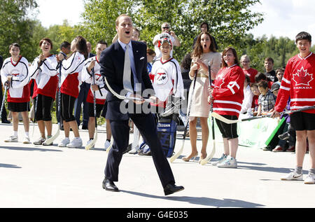 Le duc de Cambridge prend une photo avec un bâton de hockey alors que sa femme, la duchesse de Cambridge, observe lors d'une visite à la Somba K'e Civic Plaza à Yellowknife, dans les Territoires du Nord-Ouest. Banque D'Images