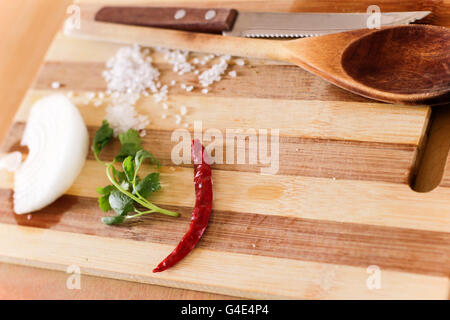 Photographie d'une table en bois avec un couteau, spatule, le sel, le fromage et l'oignon Banque D'Images