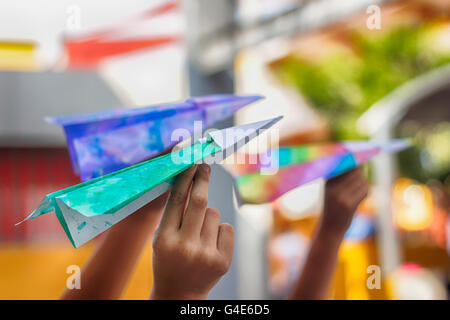 Photographie de certains avions colorés sur papier prêt à voler sur les mains des enfants Banque D'Images