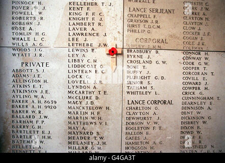 Une croix commémorative et un coquelicot à côté du nom du soldat E. Lewins, l'un des plus de 50,000 soldats britanniques et de l'Empire qui sont morts dans le Saillant d'Ypres pendant la première Guerre mondiale, dont les vestiges n'ont jamais été trouvés et qui sont commémorés à la porte Menin d'Ypres en Belgique. Banque D'Images