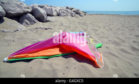 Couleur cassé abandonné un parasol à la plage de sable fin après les vacances d'été Banque D'Images