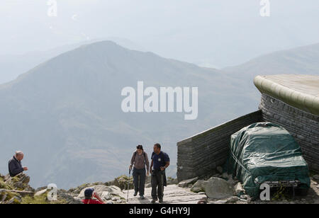 Les marcheurs au sommet du mont Snowdon à Snowdonia, au pays de Galles, se rendent devant une voiture couverte de bâche, après que le 4x4 a été abandonné près du sommet de la montagne pour la deuxième fois en un mois. Banque D'Images