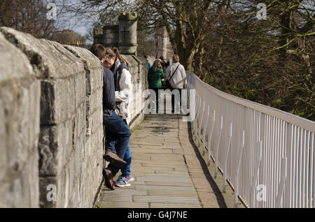 Personnes marchant sur une promenade pavée et assis sur les remparts historiques des remparts de l'ancienne cité médiévale près de Monk Bar - York, North Yorkshire, Angleterre, Royaume-Uni. Banque D'Images