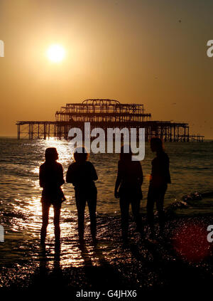 Un groupe d'étudiants regardent le soleil se coucher sur le West Pier à Brighton, dans l'est du Sussex, le dernier jour de septembre, alors que le temps chaud prévu se poursuit. Banque D'Images