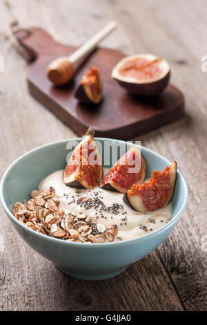 Le petit-déjeuner avec du muesli, yaourt, figues et chia graines dans un bol bleu sur un fond de bois Banque D'Images