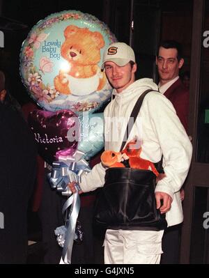 Le footballeur de Manchester United David Beckham porte des jouets et des ballons, tandis que son fiancé Spice Girl Victoria Adams se prépare à quitter l'hôpital de Portland à Londres avec le fils nouveau-né du couple, Brooklyn Joseph Beckham. Banque D'Images