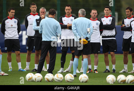 Le capitaine d'Angleterre John Terry (au centre) écoute le gérant Fabio Capello avec les joueurs (de gauche à droite) Stewart Downing (à gauche) Gary Cahill, l'entraîneur Ray Clemence, Wayne Rooney, Gareth Barry et Frank Lampard pendant la séance d'entraînement à London Colney, St Albans. Banque D'Images