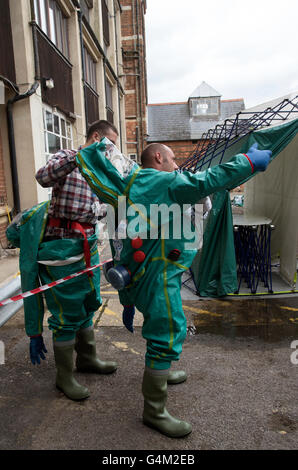 Les hommes de retirer leurs costumes de décontamination après avoir passé par une tente de décontamination Banque D'Images