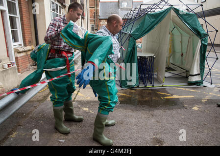 Les hommes de retirer leurs costumes de décontamination après avoir passé par une tente de décontamination Banque D'Images