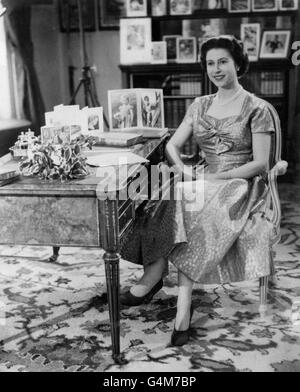 La Reine, dans une robe de couleur or, est vue dans la long Library de Sandringham peu après avoir fait la traditionnelle émission du jour de Noël à ses peuples. Sur le bureau se trouvent des portraits du prince Charles et de la princesse Anne. L'émission a été télédiffusée pour la première fois par ce yer et a été diffusée par la BBC et ITV. C'était le 25e anniversaire du premier message radio adressé au Commonwealth par son grand-père, le roi George V. Banque D'Images