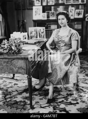 La Reine, dans une robe de couleur or, est vue dans la long Library de Sandringham peu après avoir fait la traditionnelle émission du jour de Noël à ses peuples. Sur le bureau se trouvent des portraits du prince Charles et de la princesse Anne. L'émission a été télédiffusée pour la première fois par ce yer et a été diffusée par la BBC et ITV. C'était le 25e anniversaire du premier message radio adressé au Commonwealth par son grand-père, le roi George V. Banque D'Images