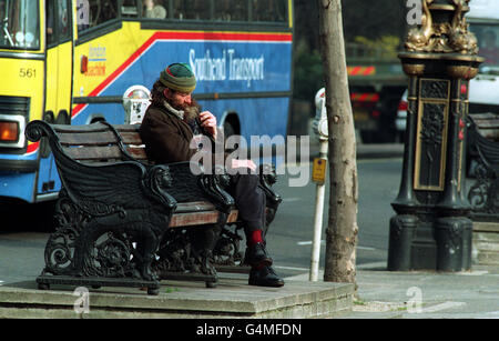 Un homme sans domicile se trouve sur un banc de parc à côté d'une rue animée de Londres.27/03/02 : Un homme sans domicile repose sur un banc de parc à côté d'une rue animée de Londres.: Une sombre photo de Londres comme ville de sans-abri, de yobs et de bigots a été peinte aujourd'hui, dans un nouveau guide touristique Lonely Planet.Le guide décrit le système de transport public de la capitale comme une mouture épuisant et épuisant.Les pigeons de Trafalgar Square sont considérés comme des rats sales et volants, tandis que les visiteurs d'Oxford Street doivent gérer le gant de fermeture permanente des ventes. Banque D'Images