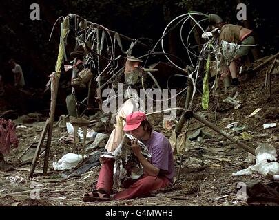 Un festif lit les restes d'un journal au coin d'un des terrains de camping du Glastonbury Festival 1999. Banque D'Images