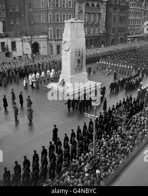 Une figure solitaire en noir, la Reine place sa couronne sur le Cenotaph quand elle dirige l'hommage de la nation aux morts de deux guerres mondiales. Le monolithe est entouré de membres du clergé, de dirigeants des partis politiques et de membres du cabinet. À gauche, à l'intérieur de la place creuse formée par les trois services, se trouvent les Ducs d'Édimbourg et de Gloucester. Banque D'Images