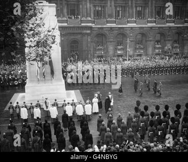 Les feuilles d'automne, symbole d'une année de mort, se brossent à travers le Cenotaph à Whitehall, Londres, alors que la Reine, une figure solitaire noire, mène l'hommage de la nation aux morts de deux guerres mondiales. Banque D'Images