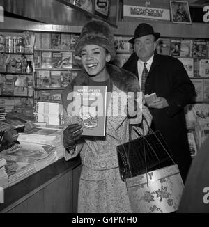 Le bouleversement de la nuit dernière apparemment oublié, la chanteuse Shirley Bassey est manifestement satisfaite de son choix de littérature à la bibliothèque de l'aéroport de Londres. Elle s'envolait à New York pour accomplir un cabaret de quatre semaines. À l'hôtel Savoy hier soir, Shirley a quitté la scène très bouleversée après s'être plainte devant son public lors d'une fête célébrant le dixième anniversaire de la course de Londres de la pièce, le Mousetrap. Shirley apparaissait dans le cabaret à la fête et pendant son acte a dit au public "c'est comme une salle de vente aux enchères à l'arrière". Banque D'Images