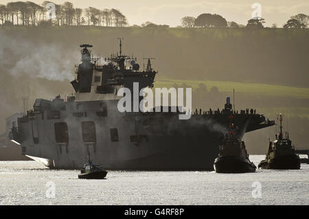 HMS Ocean arrive sur les quais de la base navale royale de Devonport Plymouth, après une visite de sept mois et demi qui a vu l'équipage lancer des assauts aériens qui ont aidé à mettre fin au régime du colonel Kadhafi en Libye. Banque D'Images