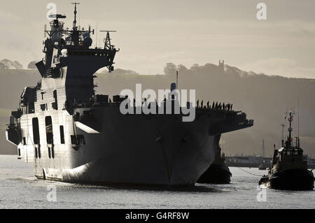 HMS Ocean arrive sur les quais de la base navale royale de Devonport Plymouth, après une visite de sept mois et demi qui a vu l'équipage lancer des assauts aériens qui ont aidé à mettre fin au régime du colonel Kadhafi en Libye. Banque D'Images