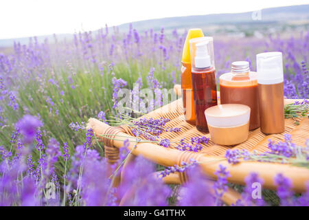 Les savons à base de fleurs et de lotions groupe dans des bouteilles sur fond de champ de lavande Banque D'Images