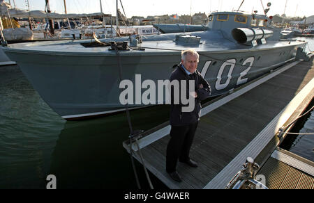 Richard Basey, se dresse le long du bateau Motor Torpedo 102, attaché à Oulton Broad, Lowestoft, Suffolk. Banque D'Images