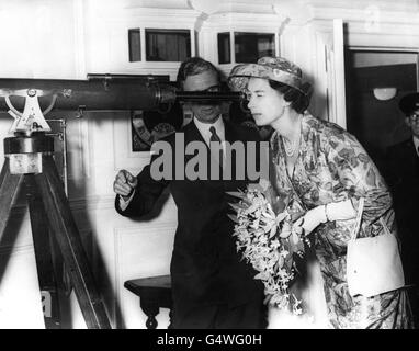 La reine Elizabeth II donne sur le télescope de la cathédrale Saint-Paul, à environ 4 kilomètres, lors d'une visite de la maison flammé restaurée, le plus ancien bâtiment de l'ancien observatoire royal de Greenwich, Londres. Elle est aidée par Frank Carr, directeur du Musée maritime national. La Maison flammé sera utilisée pour abriter une partie de la collection d'instruments appartenant au musée. Banque D'Images