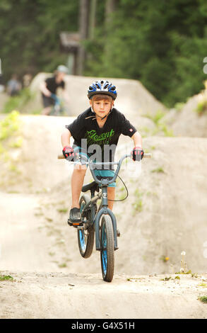 Sept ans Spencer Gogin obtient d'antenne sur le vélo le long de la rivière sauts, Fitzsimmons Creek. Whistler, BC, Canada. Banque D'Images