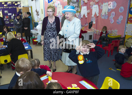 Isaac Minns, trois ans, joue jusqu'à la caméra tandis que la reine Elizabeth II visite l'école de bébé et de pépinière de Dersingham à Kings Lynn, Norfolk, à l'occasion du 60e anniversaire de son accession au trône. Banque D'Images