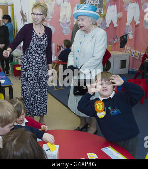 Isaac Minns, trois ans, joue jusqu'à la caméra tandis que la reine Elizabeth II visite l'école de bébé et de pépinière de Dersingham à Kings Lynn, Norfolk, à l'occasion du 60e anniversaire de son accession au trône. Banque D'Images