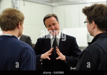 Le Premier ministre britannique David Cameron s'entretient avec les apprentis Robert Coverdale (à droite) et Tom Higgins (à gauche) lors d'une visite à la Tunneling and Underground Construction Academy, à l'est de Londres. Banque D'Images