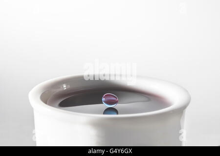 L'équilibrage des gouttelettes d'eau de couleur juste avant qu'il éclabousse dans la tasse d'eau Banque D'Images