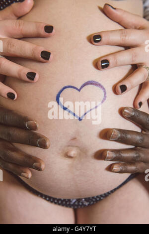 Les futurs parents sont holding pregnant belly ; d'un coeur sur le ventre. Banque D'Images