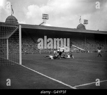 Le gardien de but né en Allemagne à Manchester City, Bert Trautmann, fait un dernier pas sous les pieds de Birmingham City à l'intérieur de gauche Peter Murphy lors de la finale de la coupe FA à l'Empire Stadium, Wembley, Londres. * c'était l'une des trois occasions dans lesquelles le gardien de but a été blessé en faisant une sauvegarde. Cette fois, il a soutenu un cou cassé mais a porté sur bien qu'à moitié conscient. Son courage a été récompensé. Manchester City a remporté le match 3-1 Banque D'Images