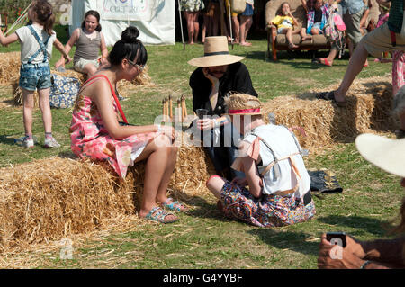 La fête des familles sur les balles de foin en face de tentes de divertissement au Port Eliot Cornwall Festival Banque D'Images