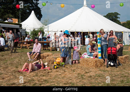 La fête des familles sur les balles de foin en face de tentes de divertissement au Port Eliot Cornwall Festival Banque D'Images