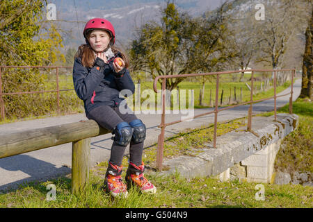 Joli préadolescent avec roller skate casque, mangez une pomme Banque D'Images