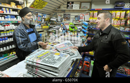 M. Tajinder Sagoo (à gauche) vend des copies à un client du nouveau Sun le dimanche dans son magasin South Woodford News, le jour de la première édition du titre. Banque D'Images