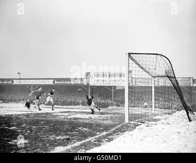 Le NAT Lofthouse de Bolton Wanderers a passé Ron Baynham, gardien de but de Luton Town, pour gagner la cravate. Banque D'Images