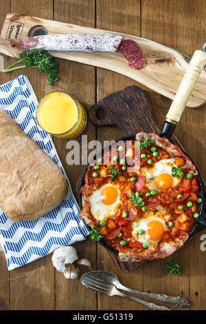 Oeufs cuits au four avec du chorizo, pommes de terre et les tomates dans une casserole sur la table. Vue de dessus Banque D'Images