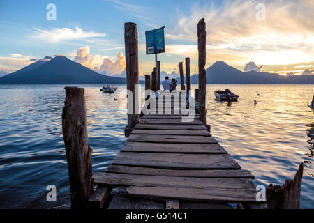 Un couple de touristes s'asseoir sur le quai à Panajachel au coucher du soleil sur le Lago de Atitlan, un lac de cratère volcanique au Guatemala Banque D'Images