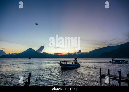 Le soleil se couche sur le Lago de Atitlan au Guatemala, et la dernière des taxis d'eau mettre les touristes vers les docks de Panajachel au crépuscule. Banque D'Images