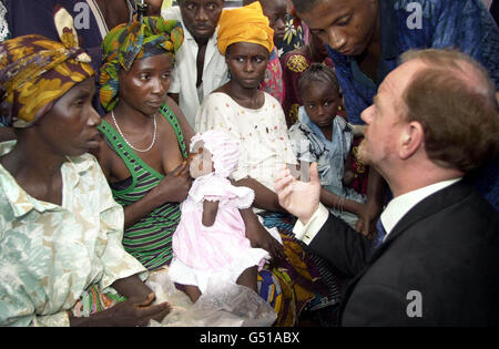 Mari Koroma, âgé de huit mois, dont la main a été prise par les rebelles à l'âge de 3 mois, est allaitée au sein lors d'une visite du ministre britannique des Affaires étrangères Robin Cook, à droite, dans un camp de réfugiés pour les victimes amputées de la guerre civile, à Freetown, en Sierra Leone. Banque D'Images