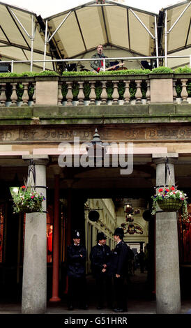 Le chanteur Fran Healy, du groupe pop Travis, se produit sur le toit de la place Covent Garden à Londres, tandis que trois policiers en bas se tiennent en service. Le concert a été organisé dans le cadre du festival national de musique BBC Music Live. Banque D'Images