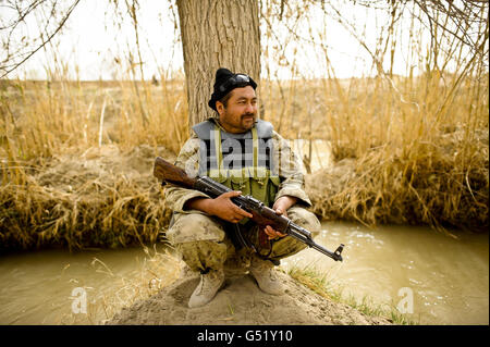 Un membre de la police civile de l'ordre national de l'Afghanistan (ANCOP) repose sous un arbre dans une chaleur de 32 degrés tandis qu'il regarde la région de Yakhchal de la province de Helmand sur l'opération 'Now Roz' (qui signifie le nouveau jour à Dari), Rechercher des composés à la recherche d'usines soupçonnées d'IED et de preuves d'une activité insurgée en Afghanistan. Banque D'Images