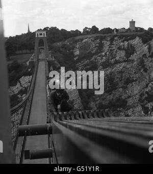 Ce n'est pas le cas pour les hommes qui obtiennent des sorts de giddy, mais M. Gilbert Taylor (plus proche) et M. Alfred Stadon sont maintenant bien habitués aux hauteurs.Ce sont les hommes d'entretien résidents qui s'intéressent à plein temps au célèbre pont suspendu de Clifton, au-dessus du port de Bristol.Ils sont vus au travail avec leurs bidons d'huile sur les « chaînes » au-dessus de la chaussée. Banque D'Images
