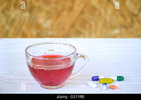 Tasse de thé hibiscus en transparent tasse sur nappe blanche, servi avec les compléments alimentaires Banque D'Images