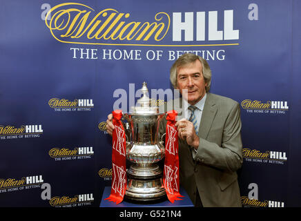 L'ancien gardien de but Tottenham, Arsenal et Irlande du Nord Pat Jennings, qui a remporté la coupe avec les deux clubs en 1967 et 1979, pose avec la coupe FA dans le magasin de Paris de William Hill à Tottenham High Road dans le nord de Londres. Banque D'Images